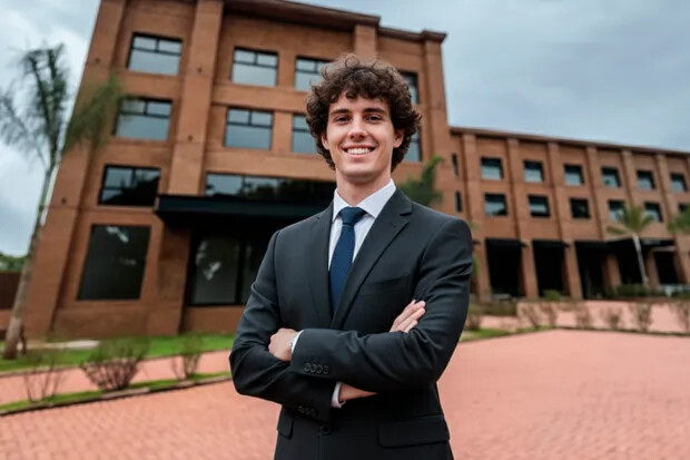 Estudante sorrindo em frente ao prédio da Faculdade Themis